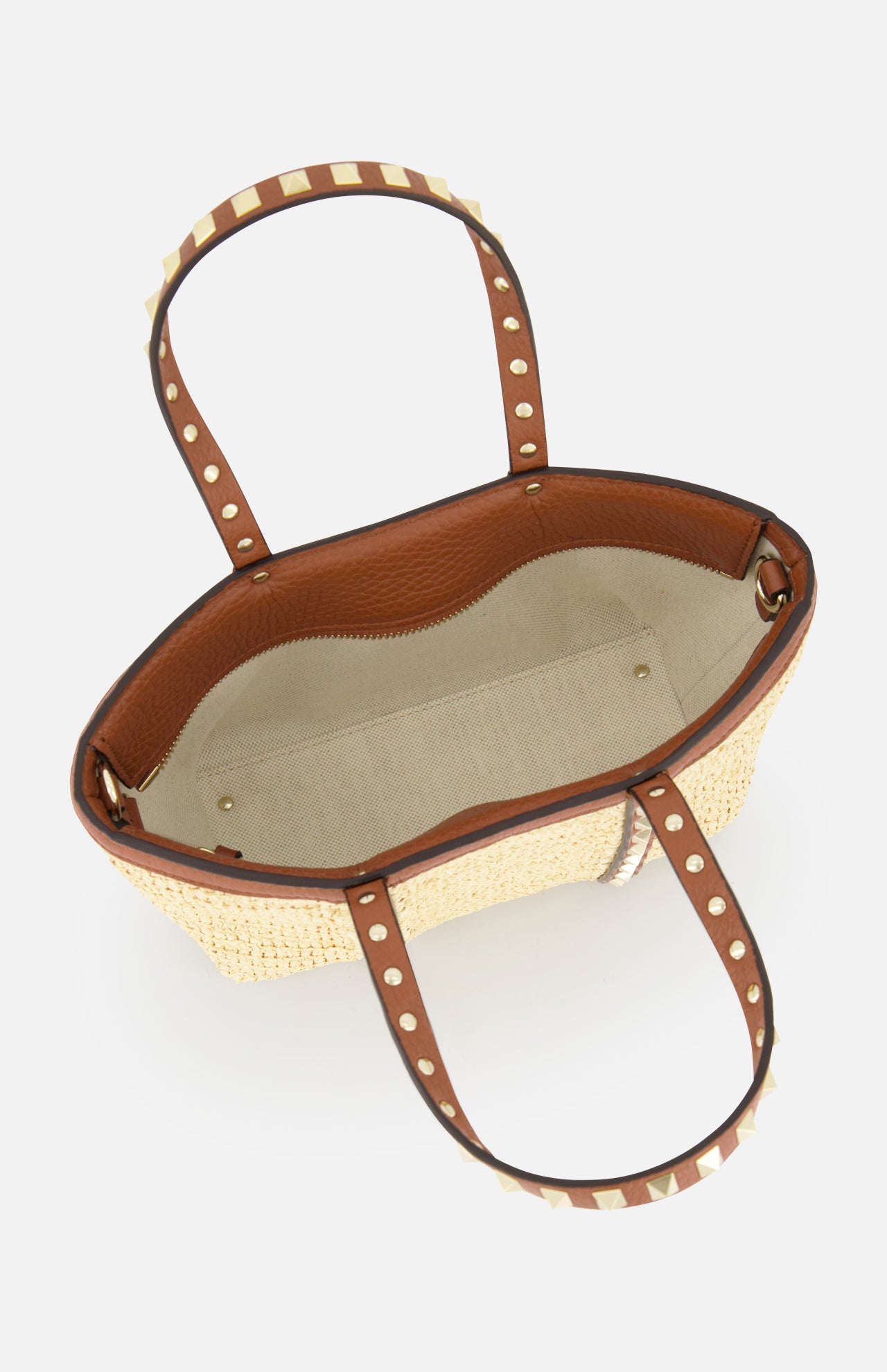 Top view of VALENTINO GARAVANI Rockstud Mini Tote Bag, featuring raffia and brown leather with gold rockstud handles, beige fabric lining, and an interior zipper pocket.