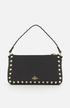 The Rockstud Small Shoulder Bag by VALENTINO GARAVANI is a black leather shoulder bag with gold-tone rockstud trim, a removable strap, and a small gold logo on the front.