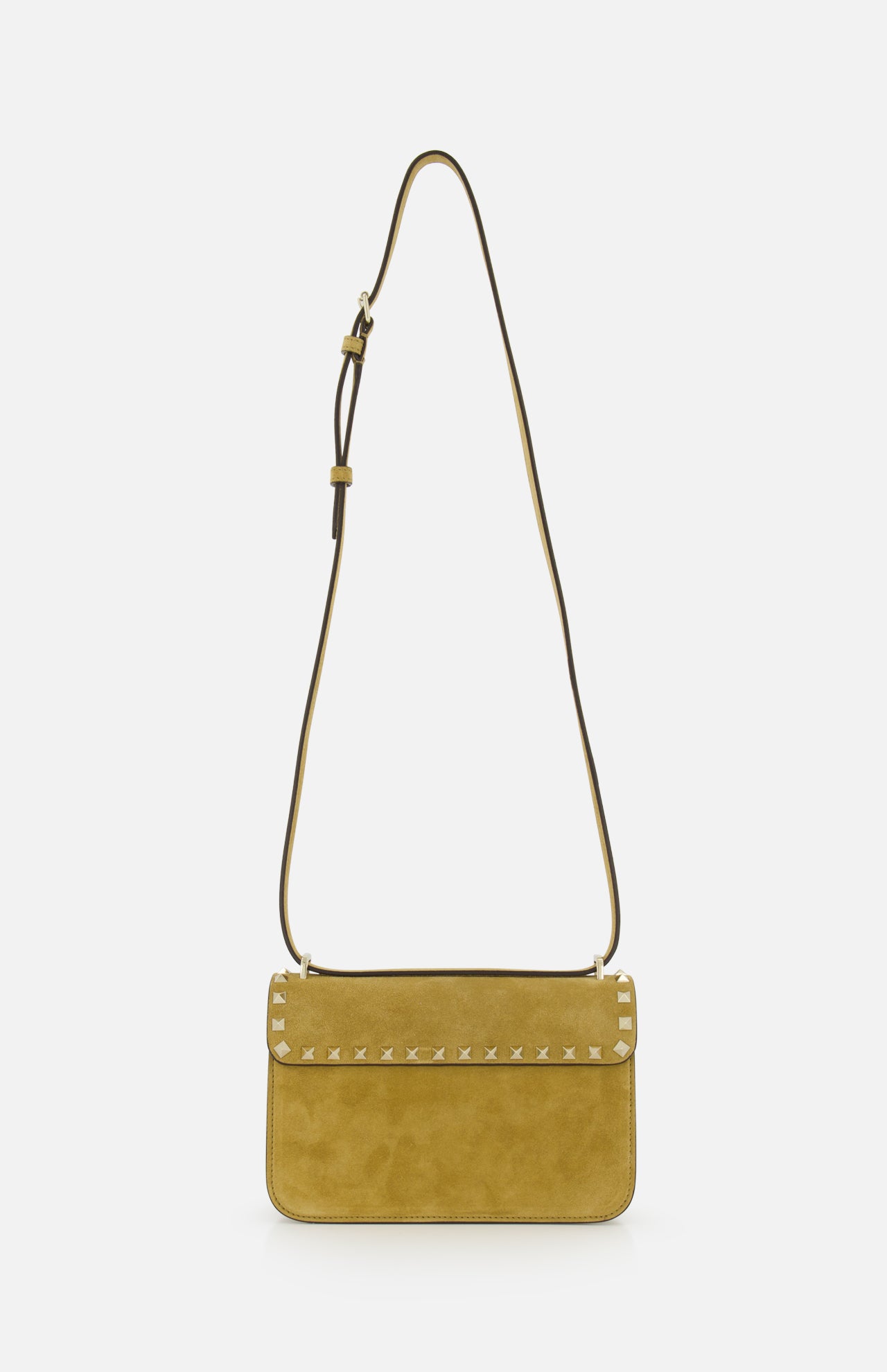 The VALENTINO GARAVANI Rockstud Small Shoulder Bag in mustard yellow suede features a flap closure, gold-tone rockstud trim along the edge, and an adjustable strap. It is displayed against a plain white background.