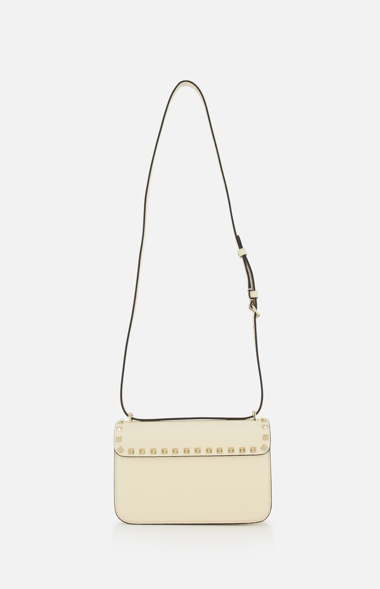 Valentino Garavani Rockstud Small Shoulder Bag in off-white ivory leather with a thin adjustable strap and a row of gold pyramid studs along the front flap.