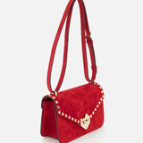 The VALENTINO GARAVANI Rockstud Small Suede Shoulder Bag features lipstick red suede, rockstud trim on the flap, a gold clasp closure, and an adjustable strap.