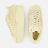 The VALENTINO GARAVANI Royco Shearling Platform Sneaker is pictured in a pair, each showcased from the side and top view. The sneakers feature cream-colored, soft shearling uppers with light-toned laces and thick platform soles. Subtle logo detailing accents the design, all set against a white background.