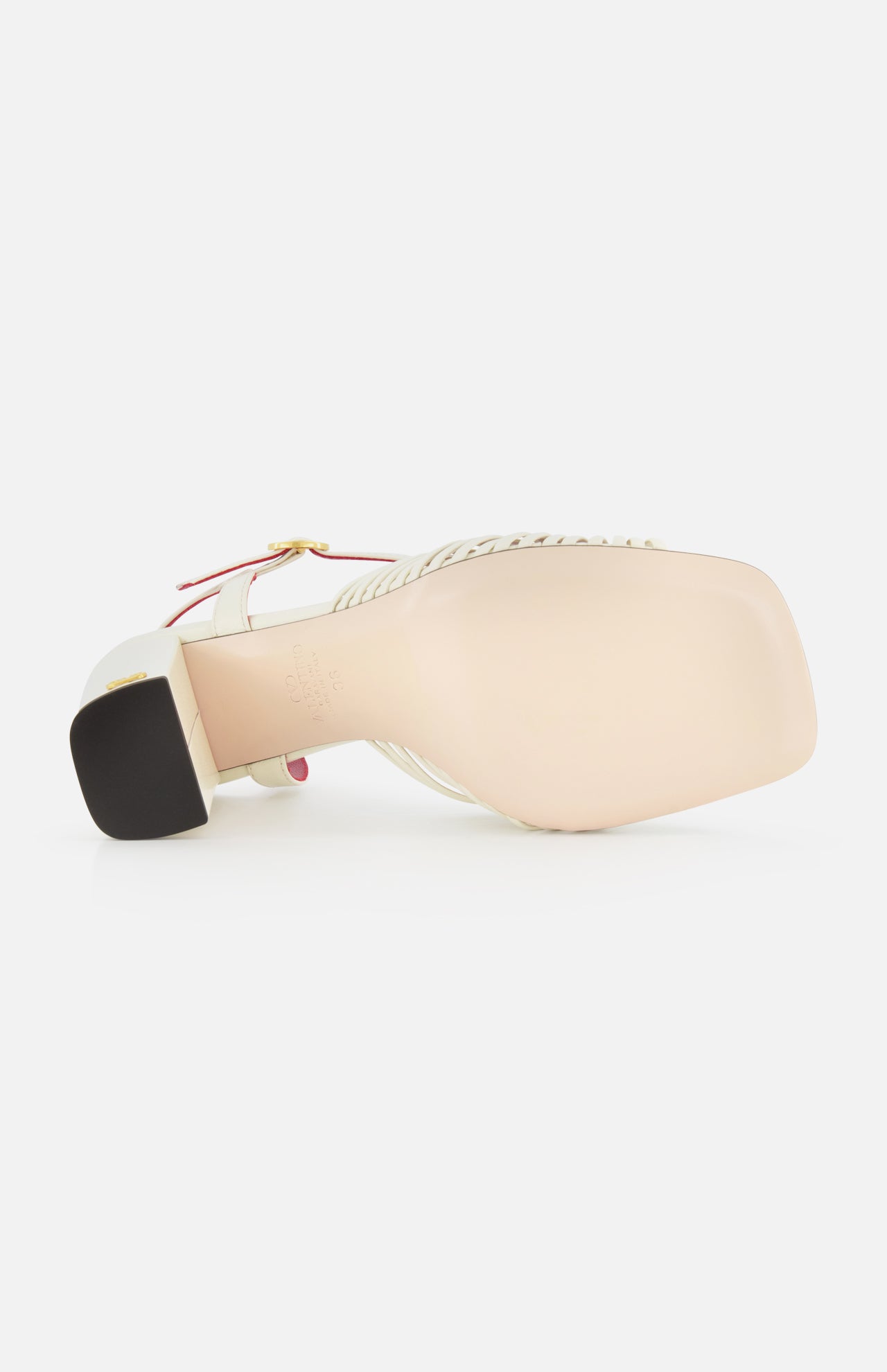A close-up of the Valentino Garavani Annet T.90 Sandal by VALENTINO GARAVANI, featuring a white leather ankle strap with gold buckle, ivory heel, light pink sole, and square toe.