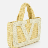 The VALENTINO GARAVANI Viva Superstar Crochet Small Tote Bag features woven straw, two short handles, and a bold white outlined VLogo on the front, shown against a white background.