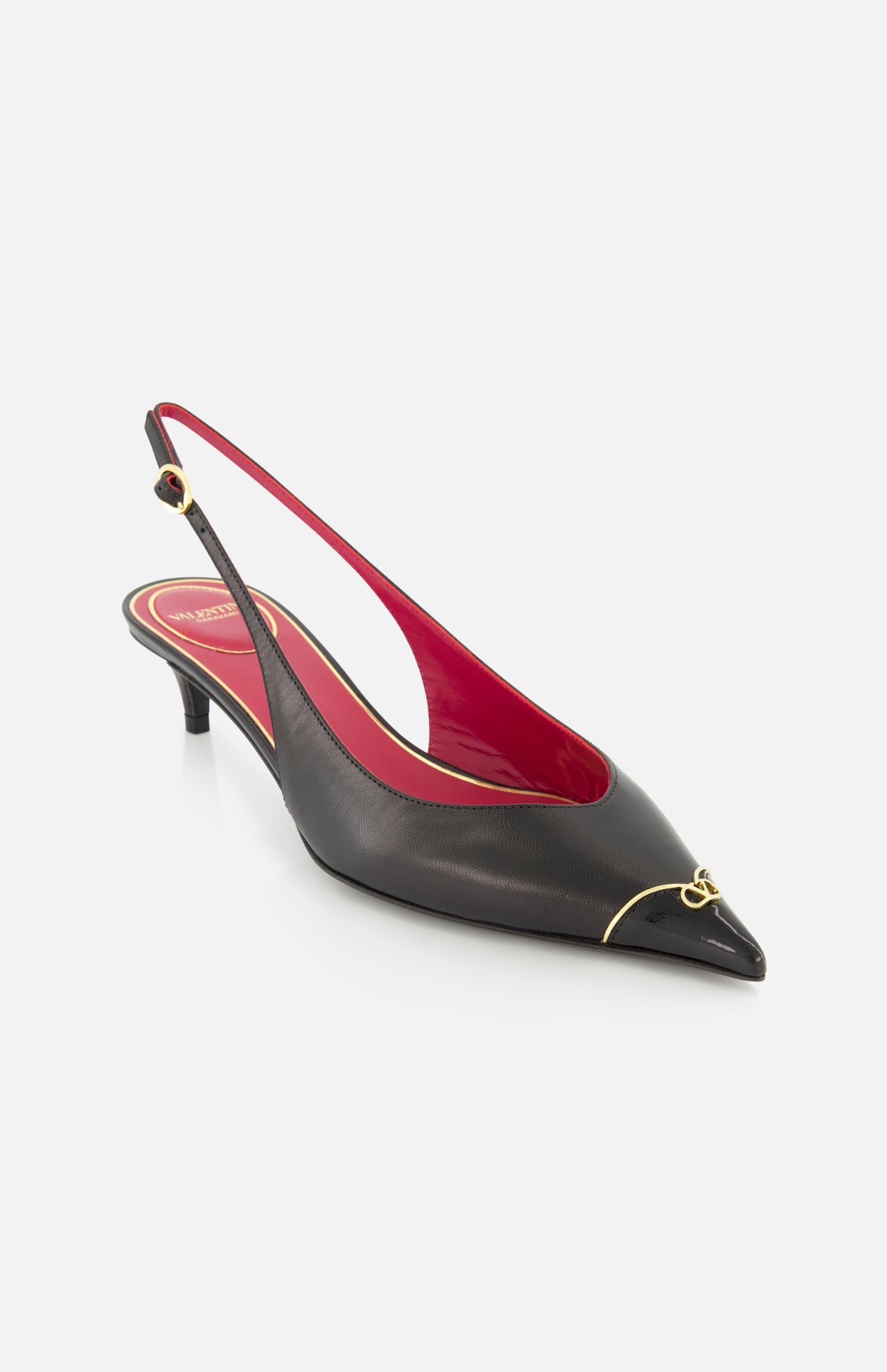 The VALENTINO GARAVANI VLogo Heartip Sling Back Heel is a black Italian leather heel with a pointed toe, low kitten heel, red lining, gold toe accent, and adjustable ankle strap.