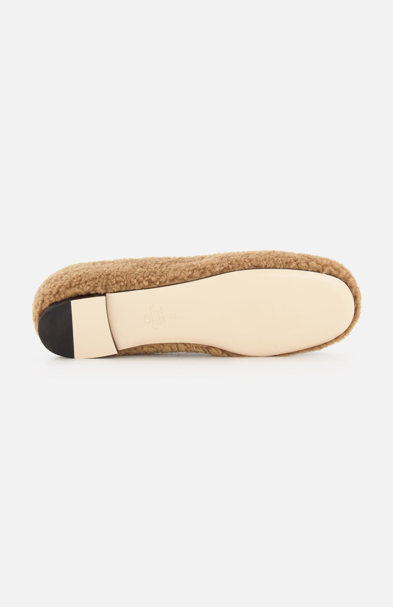 The image shows the bottom view of the VLogo Signature Ballerina Flat by VALENTINO GARAVANI, featuring a tan shearling design with a beige sole and a black heel cap, photographed against a white background.