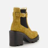 The VALENTINO GARAVANI VLogo Signature Beatle Boot is a pair of beige Chelsea boots crafted from tan suede, featuring a chunky black heel and sole, black elastic side panels, sleek gold buckle detail inspired by VLogo hardware, and a plush white fleece lining—all showcased against a white background.