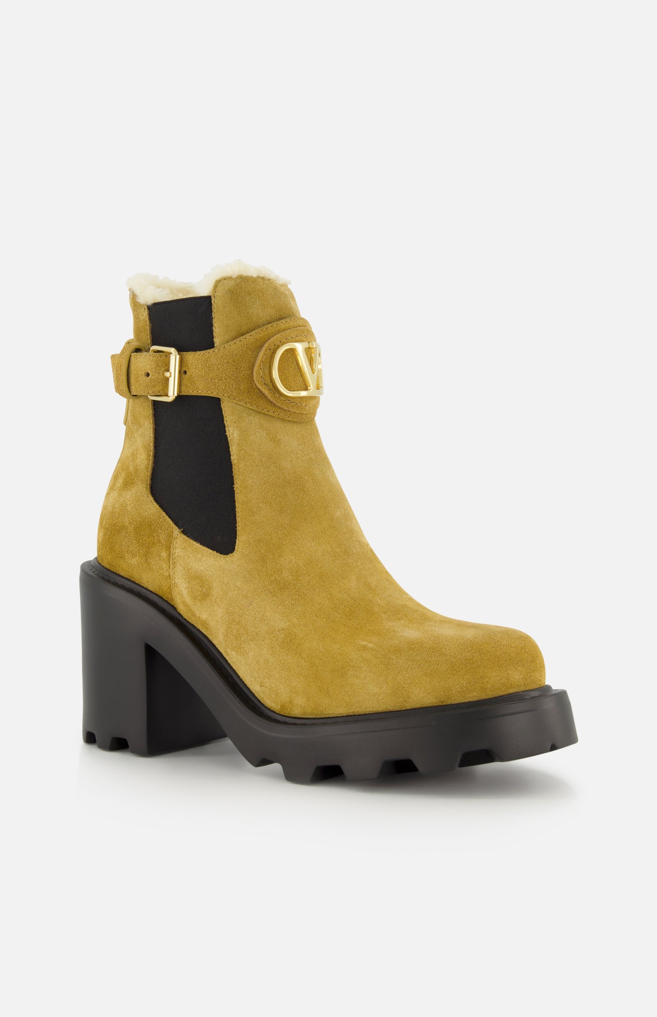 The VLogo Signature Beatle Boot by VALENTINO GARAVANI features tan suede with a chunky black heel and sole, gold buckle detail, black elastic side panel, and visible shearling lining at the top—these chic ankle boots offer a stylish twist on classic design.