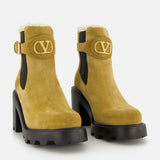 Step up your style with the VALENTINO GARAVANI VLogo Signature Beatle Boot: a pair of mustard yellow suede ankle boots featuring chunky black heels and soles, gold buckles, black side panels, and striking gold VLogo hardware on the front—offering a bold twist on classic style.