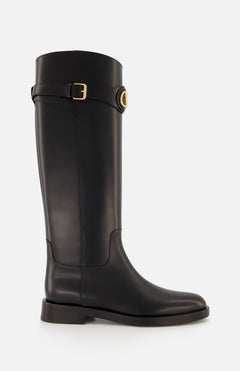 The VALENTINO GARAVANI VLogo Signature Boot is a black knee-high leather riding boot with a low heel, rounded toe, and gold-tone buckle detail at the top, shown against a plain white background.