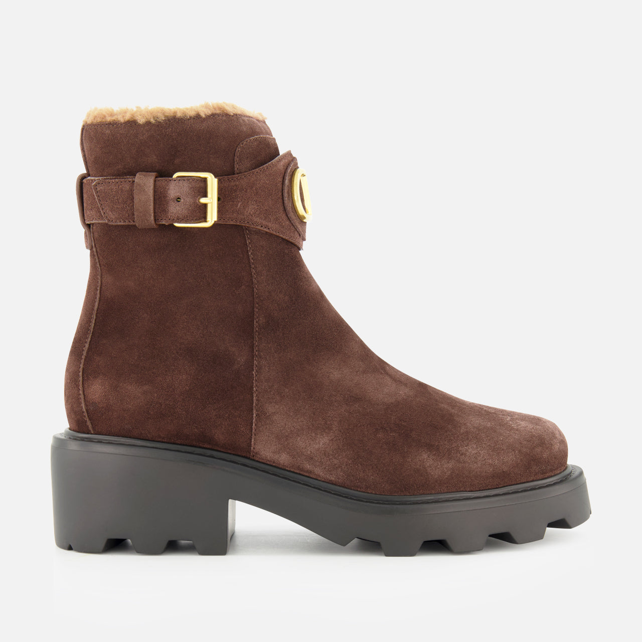 The VALENTINO GARAVANI VLogo Signature Sheepskin Bootie, featuring brown suede, a chunky black sole, luxurious sheepskin lining, and an elegant gold buckle, is showcased in side profile against a white background—an ideal fall choice for stylish comfort.
