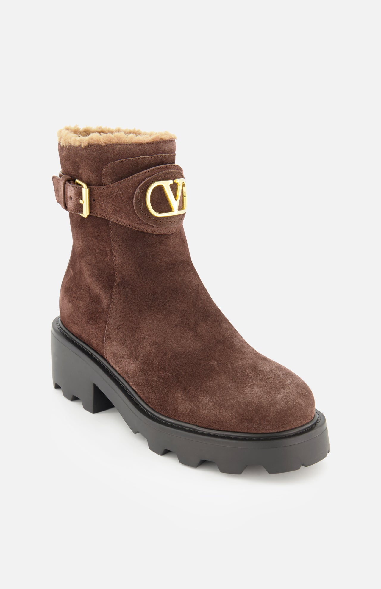 The VLogo Signature Sheepskin Bootie by VALENTINO GARAVANI features luxurious brown suede, a chunky black sole, a gold buckle, plush sheepskin lining for warmth, and the signature gold V logo on the side—making it the perfect addition to your fall boots collection.
