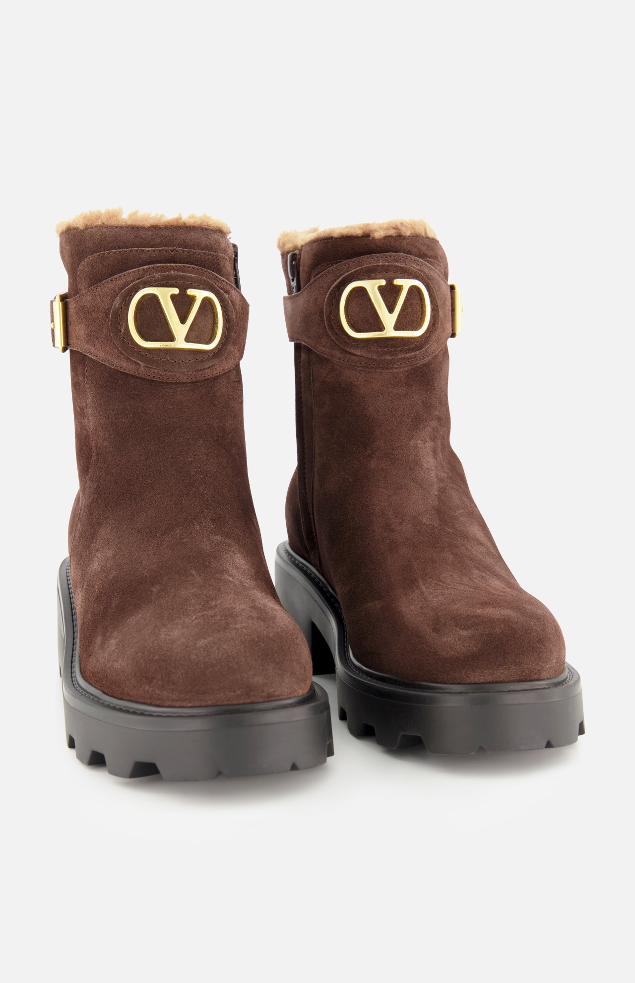 The VALENTINO GARAVANI VLogo Signature Sheepskin Bootie is a pair of brown suede ankle boots with chunky black soles, gold VLogo buckles, and light tan sheepskin lining at the tops—making these suede booties perfect for fall—shown against a plain white background.