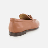 The VALENTINO GARAVANI VLogo Signature Loafer is shown at a back side angle against a white background, highlighting its light brown leather construction with an almond-shaped toe, low dark sole, and distinctive gold buckle detail on the upper front.