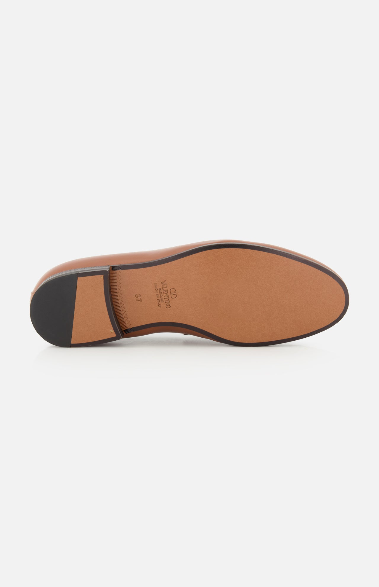 The image features the sole of the VALENTINO GARAVANI VLogo Signature Loafer, crafted in brown leather with a black heel and a smooth tan surface. Viewed from the bottom against a white background, the sole’s elegant design suggests an almond toe silhouette that embodies both style and sophistication.