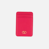 The VALENTINO GARAVANI VLogo Signature Magnetic Card Holder, crafted in bright pink leather, features two card slots and a gold Valentino logo at the bottom center. Displayed on a white background, this elegant accessory combines style and functionality in one chic design.