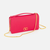 A VALENTINO GARAVANI VLogo Signature Wallet with Strap in bright pink, featuring a gold chain strap and VLogo signature detail on the front, displayed against a plain white background.