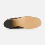 A close-up view of the sole of the VALENTINO GARAVANI Zimmy Western Bootie showcases a smooth tan leather bottom and a black heel, evocative of classic western boots, photographed against a plain white background.