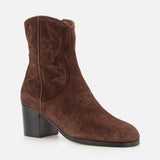 The Zimmy Western Bootie by VALENTINO GARAVANI showcases dark brown suede with a medium block heel, subtle decorative stitching, and a rounded toe reminiscent of classic western boots, presented against a white background.