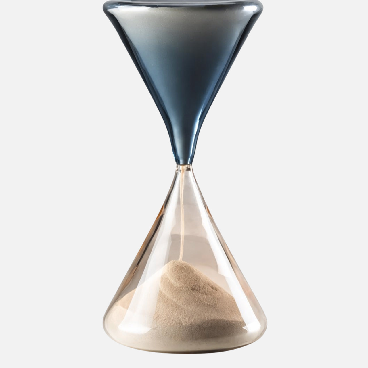 The VENINI Clessidra Hour Glass features a Murano glass design with a dark blue top, clear bottom, and light sand settled below, displayed against a plain white background.