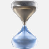 The Clessidra Sommersa Hour Glass by VENINI features a modern metallic Murano glass design with a smooth, reflective surface—silver on top and blue-tinted below. The empty hourglass is shown against a plain white background.