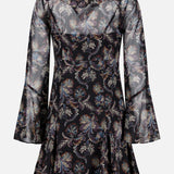 The Adrienne Paisley Mini Dress by VERONICA BEARD features sheer long sleeves, black silk fabric adorned with a colorful paisley pattern, a fitted waist, and a flared hem, displayed on a plain background.