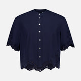 The Aleck Scalloped Embroidery Shirt by VERONICA BEARD is a navy, cotton poplin blouse with short sleeves, a button-down front, scalloped lace embroidery at the hem and sleeves, and decorative cut-out details. Displayed on a white background.