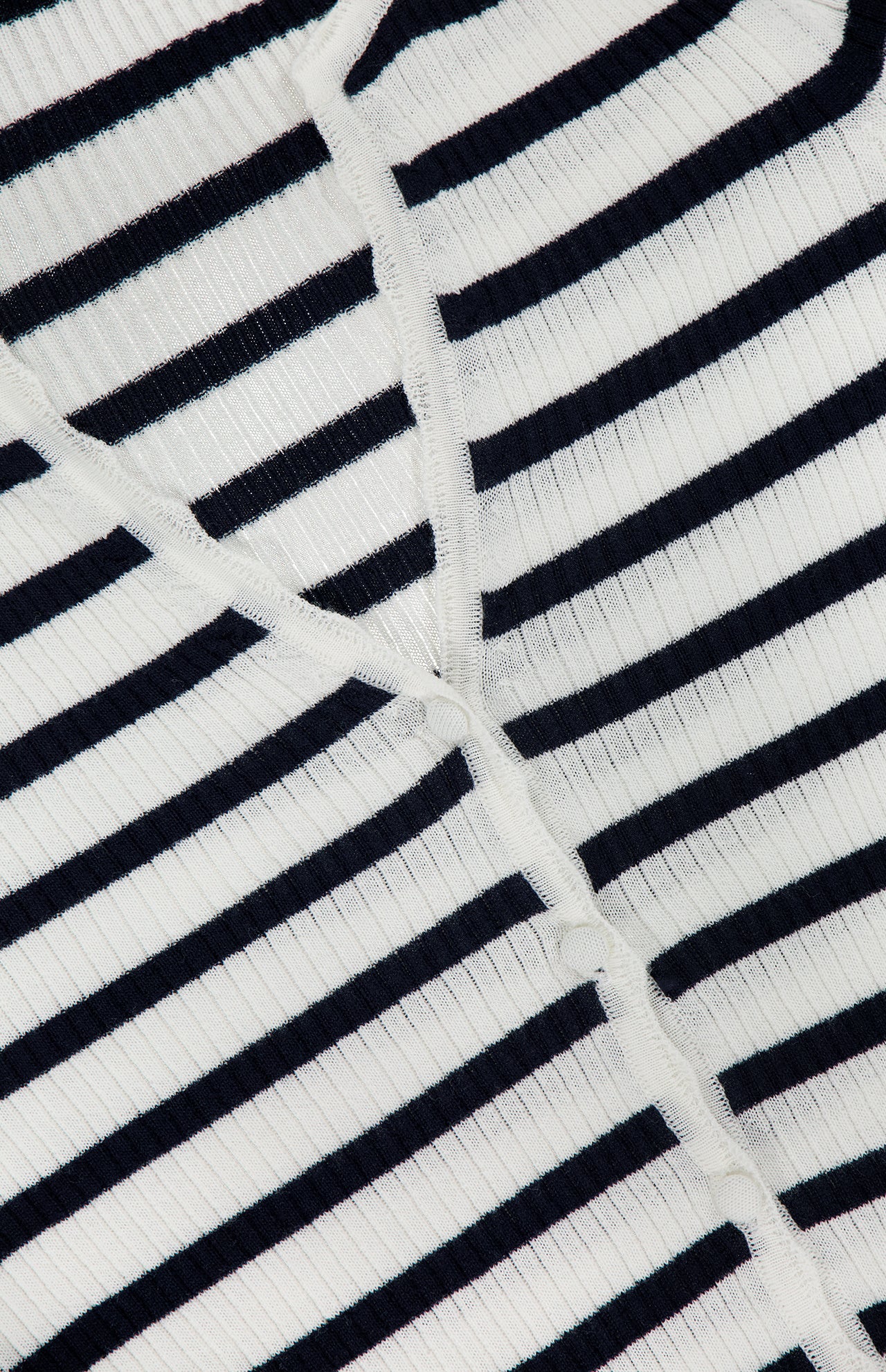 Close-up of the Anwin Scallop Trim Cardigan by VERONICA BEARD, featuring white ribbed fabric with evenly spaced horizontal black stripes and intersecting seams for a classic look.