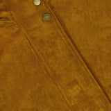 Close-up of brown suede fabric with a seam and three metallic snap buttons, highlighting the texture and rich color of the material—showcasing the perfect details of the Bateman Cropped Suede Jacket by VERONICA BEARD, ideal as fall outerwear.