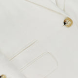 Close-up of the VERONICA BEARD Battista Dickey Jacket in white, highlighting its lapel, front pocket, tan buttons, and smooth stretch fabric for refined tailoring and a comfortable fit.