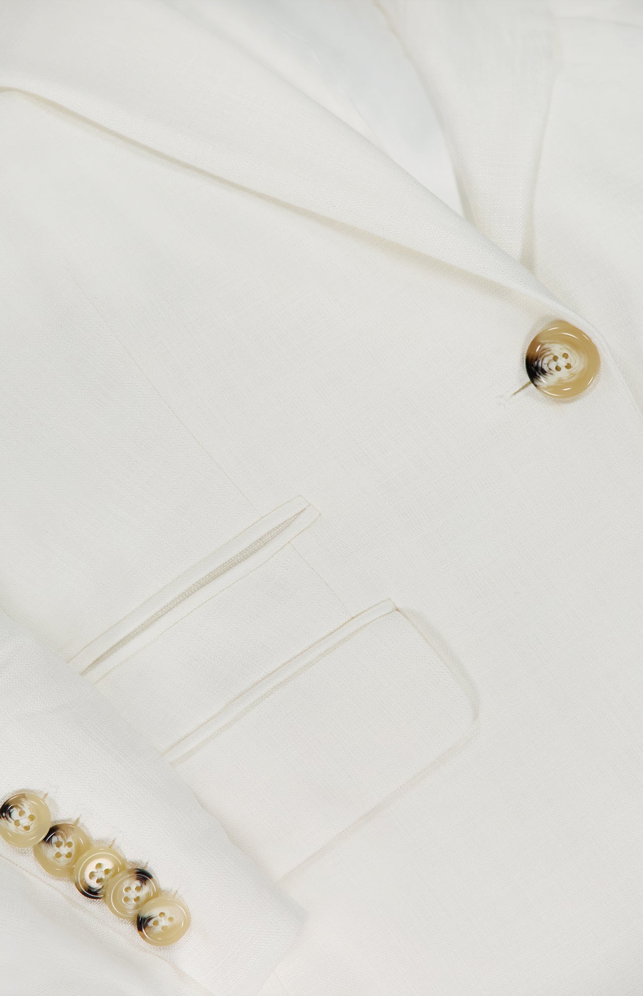 Close-up of the VERONICA BEARD Battista Dickey Jacket in white, highlighting its lapel, front pocket, tan buttons, and smooth stretch fabric for refined tailoring and a comfortable fit.