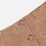 Close-up of the Callisian Leather Midi Skirt by VERONICA BEARD, crafted from tan lambskin suede with seam details, gold ring buttons, and two slanted front pockets, set against a white background.