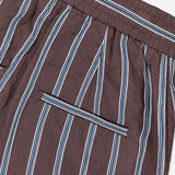 Close-up of the VERONICA BEARD Carraway Pant: brown wide-leg style with vertical white and blue stripes, elastic waistband, and a horizontal back slit pocket.