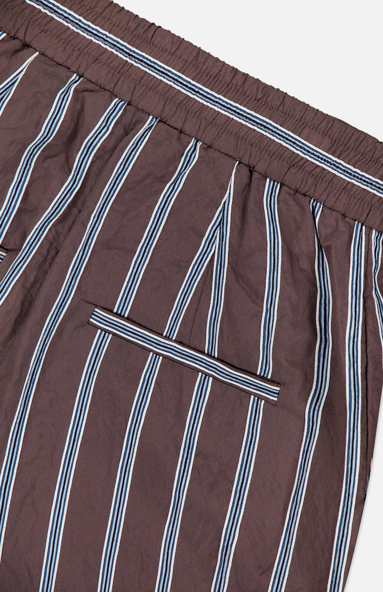 Close-up of the VERONICA BEARD Carraway Pant: brown wide-leg style with vertical white and blue stripes, elastic waistband, and a horizontal back slit pocket.