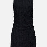 The Charissa Ruched Mini Dress by VERONICA BEARD is a sleeveless black textured mini dress featuring a round neckline, ruched sides, and a fitted silhouette, displayed against a plain light gray background.
