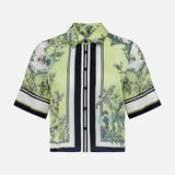 The VERONICA BEARD Clean Spruce Cropped Top is a short-sleeve, boxy fit button-down blouse in light green with a botanical floral print, black vertical stripes, and white and black trim on the sleeves and front.