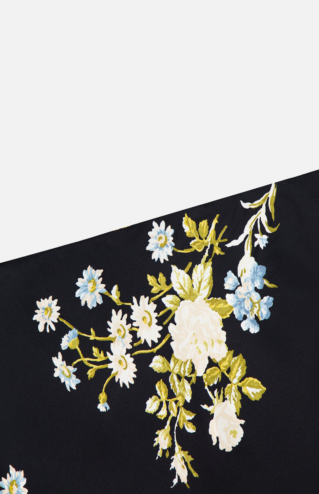 The Clover Floral Midi Skirt by VERONICA BEARD features a diagonal section of black stretch georgette fabric adorned with a floral pattern of white and blue flowers with green leaves, set against a plain white background.