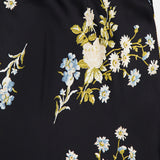 A close-up of the Clover Floral Midi Skirt by VERONICA BEARD, crafted from black stretch georgette fabric with a floral print featuring white, blue, and yellow flowers and green leaves—perfect for adding a fresh touch to your wardrobe.