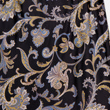 A close-up of the VERONICA BEARD Clover Paisley Midi Skirt, featuring an ornate gold, blue, and beige paisley pattern with swirling leaves and floral motifs on a black background.