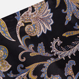 A close-up of the VERONICA BEARD Clover Paisley Midi Skirt in black silk, featuring an intricate blue, gold, and white paisley pattern with swirling floral motifs—perfect for a 90s-inspired look.