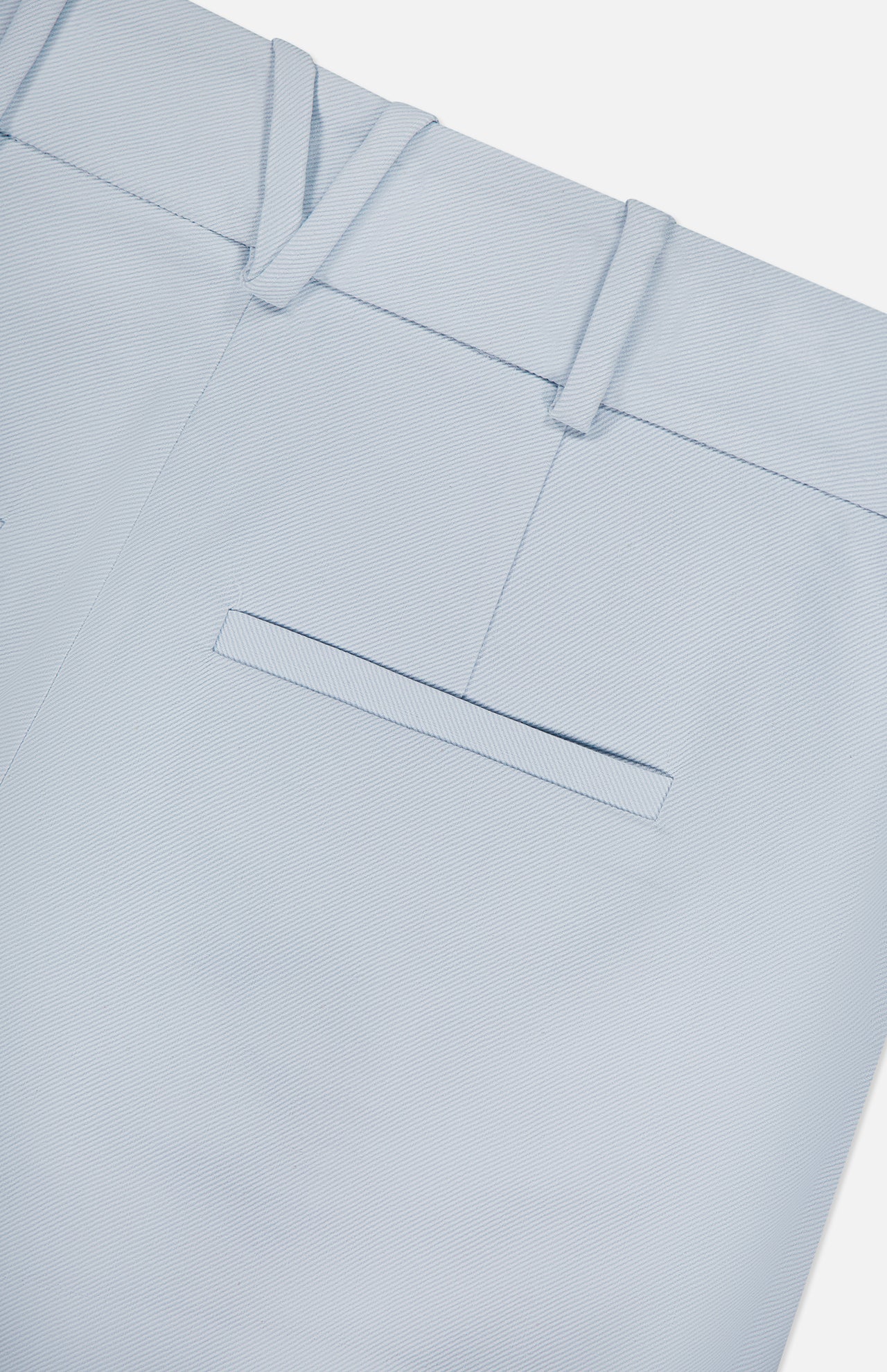 Close-up of the Craig High Rise Short by VERONICA BEARD in light blue Italian cotton-blend twill, featuring a waistband with belt loops and a single welt back pocket, shown on a white background.