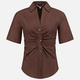 The Devra Short Sleeve Ruched Top by VERONICA BEARD is a brown, short-sleeved button-down with a collar and front-center ruching, crafted from stretch cotton poplin and shown on a plain white background.