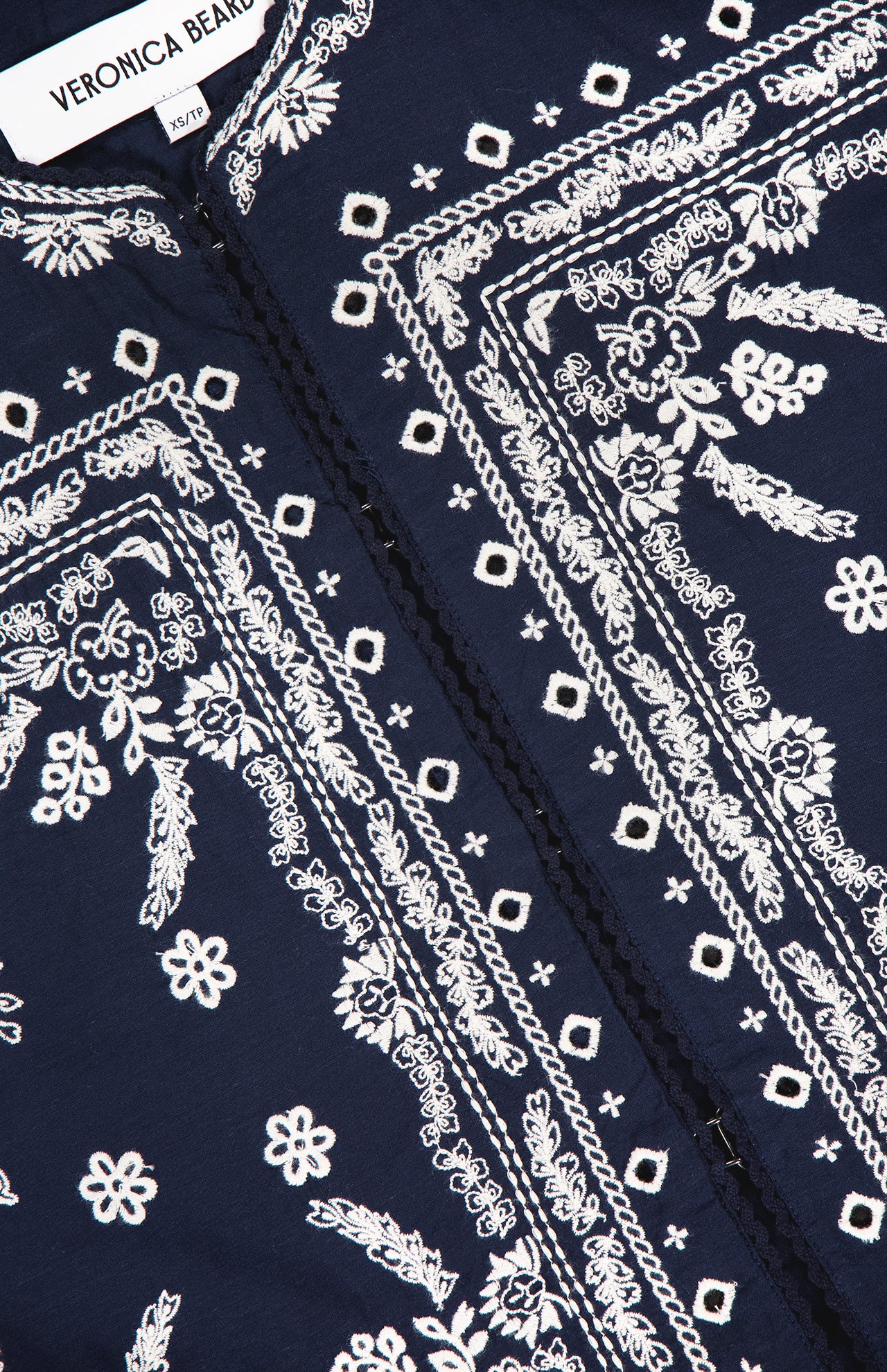 Close-up of the VERONICA BEARD Drake Embroidered Balloon Sleeve Jacket in navy, showcasing intricate white floral and geometric embroidery with a visible brand label.
