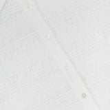 Close-up of the Ellisandra Slim Smocked Top by VERONICA BEARD, showing its textured, lace-like fabric, classic button-up placket, and part of its collar in white.