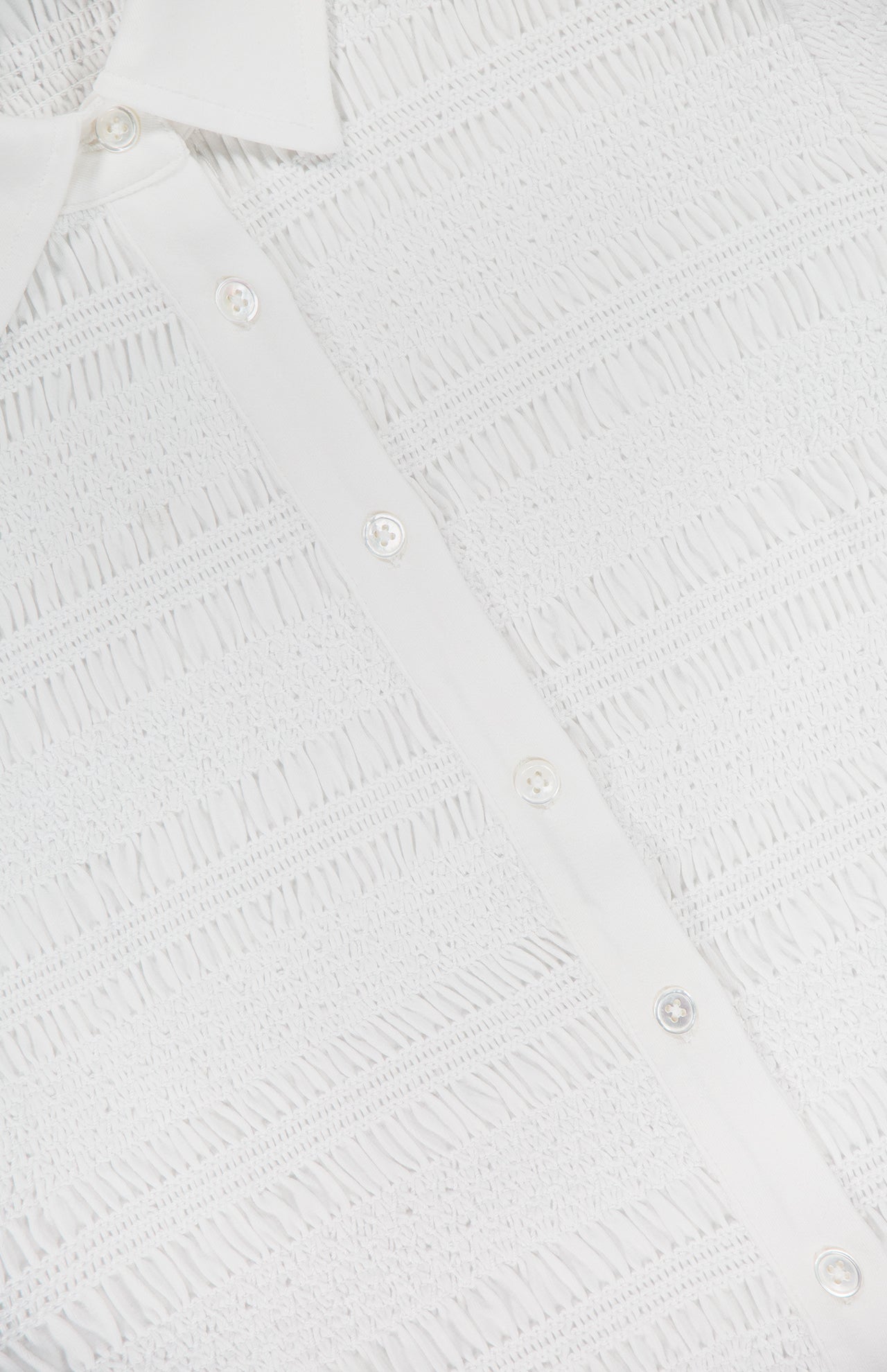 Close-up of the Ellisandra Slim Smocked Top by VERONICA BEARD, showing its textured, lace-like fabric, classic button-up placket, and part of its collar in white.
