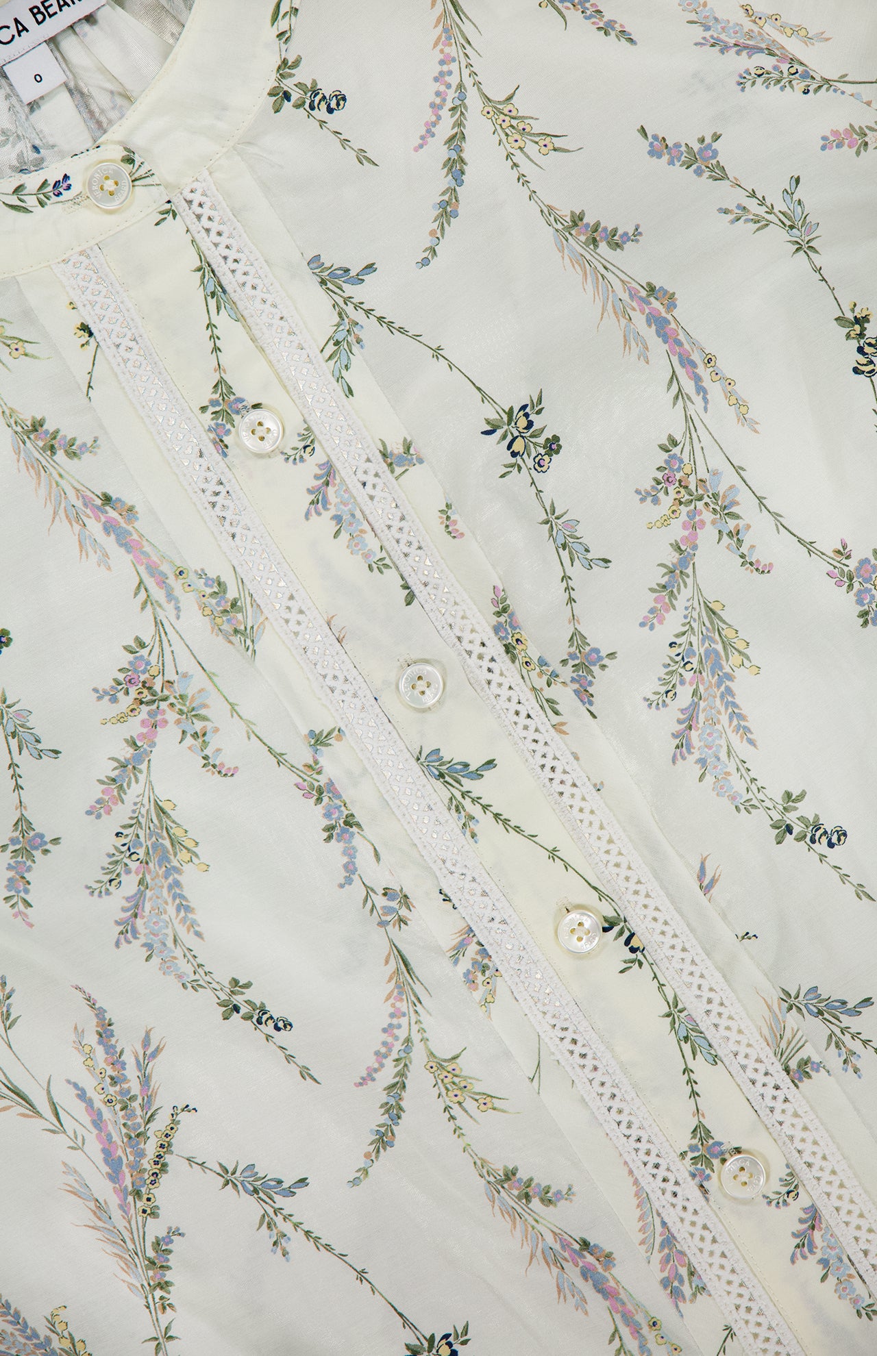 Close-up of the Emiko Floral and Lace Blouse by VERONICA BEARD, crafted in cotton-silk voile with a pastel prairie floral print, white buttons, and lace trim along the button placket.