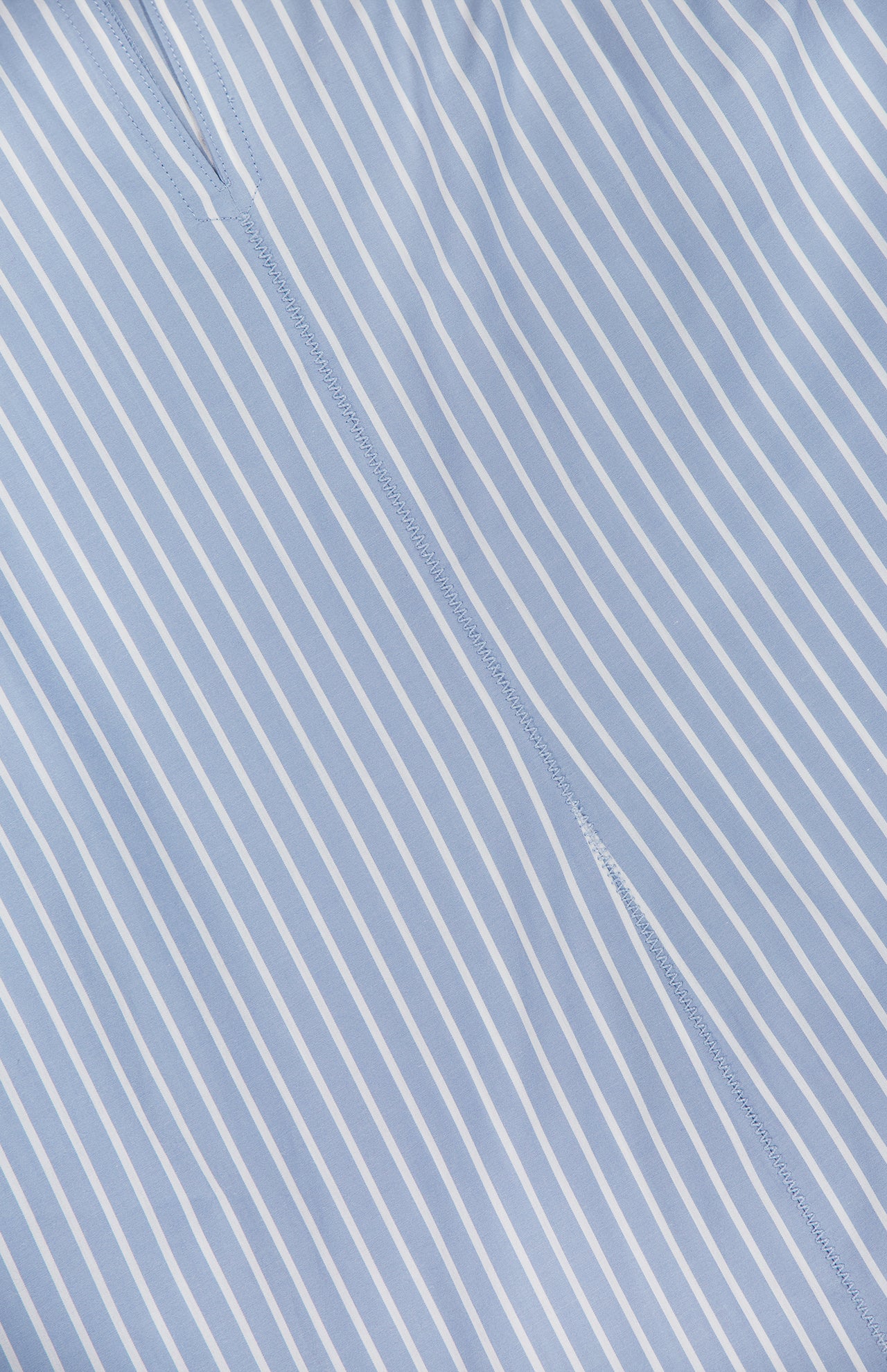 Close-up of the Florenz Striped Shift Dress by VERONICA BEARD showing light blue fabric with thin white diagonal stripes and a visible center seam, ideal for summer wear or as a chic cotton mini dress.