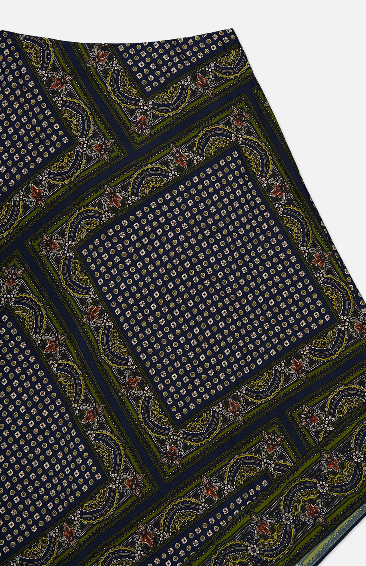 The Hartley Scarf Print Skirt by VERONICA BEARD showcases a patterned fabric in navy, green, and yellow tones with square sections of small geometric designs bordered by intricate paisley and floral motifs—ideal for an effortlessly stylish silk midi skirt or a chic statement piece.