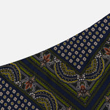 A close-up of the Hartley Scarf Print Skirt by VERONICA BEARD showcases its navy blue fabric adorned with green, white, and rust floral and geometric motifs arranged diagonally—ideal for creating a striking statement piece or styling as an elegant silk midi skirt.