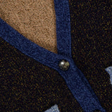 Close-up of the Josiane Cardigan Sweater from VERONICA BEARD’s knitwear collection, showcasing black and brown fabric with blue trim, two buttons, and a patch of light blue knit material for a modern colorblock effect.